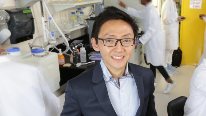 Portrait of Prof. Ngai Yin Yip in the lab with researchers in the background.