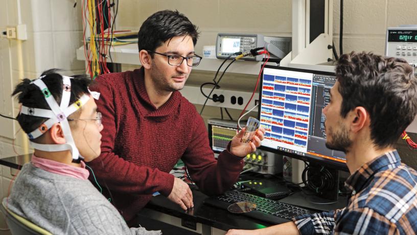 Prof. Dion Khodagholy in his lab testing biological substrates interaction with two researchers.