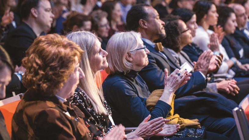 The lively and diverse audience clapping hands.