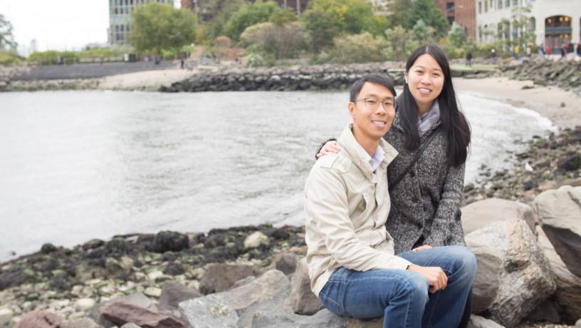 Nicholas Chack and Connie Qiu sitting by the river in Brooklyn.