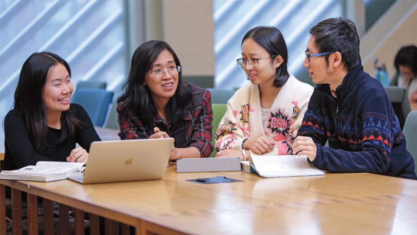 Prof. Van-Anh Truong in discussion with three PhD students.