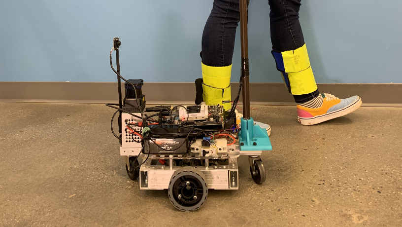 A researcher walking with the CANINE robotic cane.