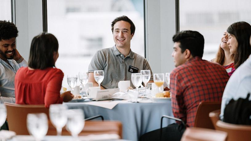 Students conversing around a table at the official MBAxMS welcome program